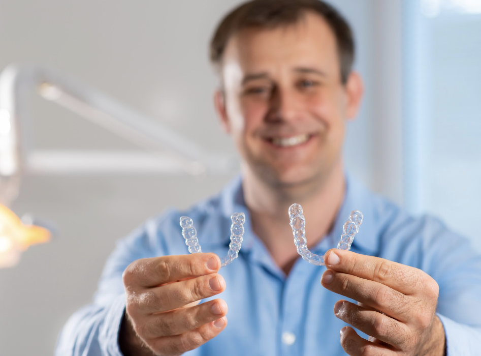 man holding 2 clear aligners